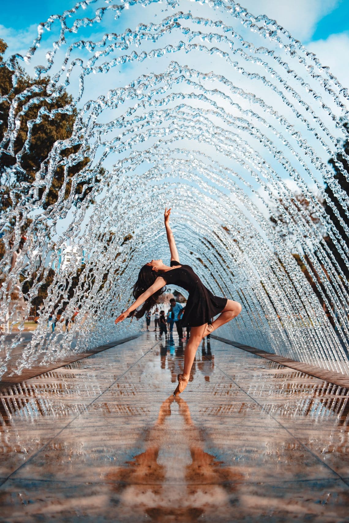 Ballet dancer, dancing in the middle of an arched water fountain.