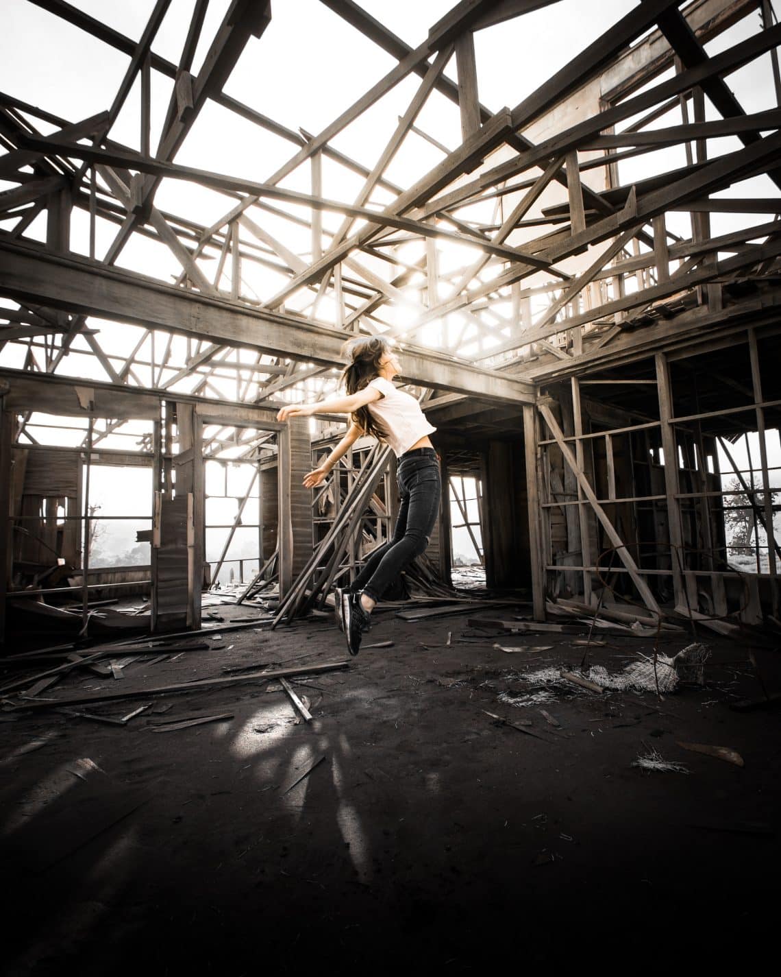 Girl flying into a beam of light in an abandoned warehouse.