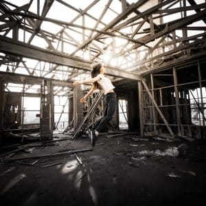 Girl flying into a beam of light in an abandoned warehouse.