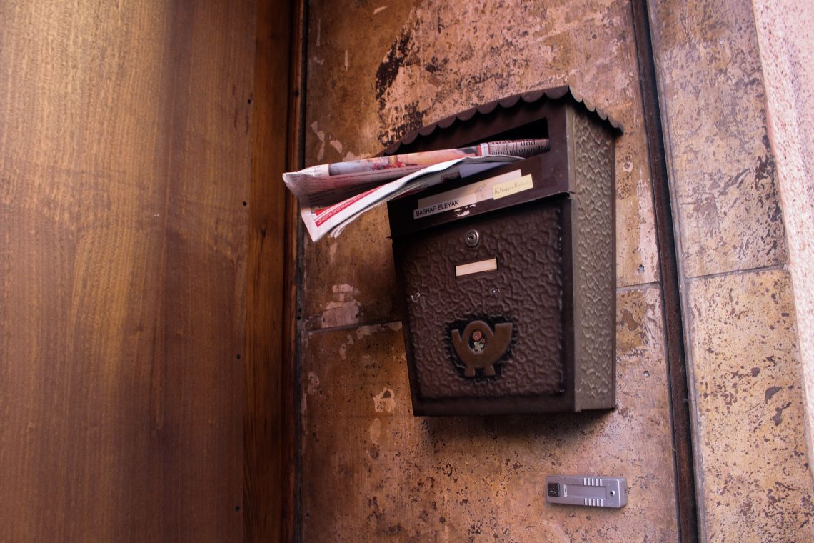 Vintage letter post box circa 1940's attached to an exterior wall overflowing with mail