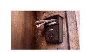 Vintage letter post box circa 1940's attached to an exterior wall overflowing with mail